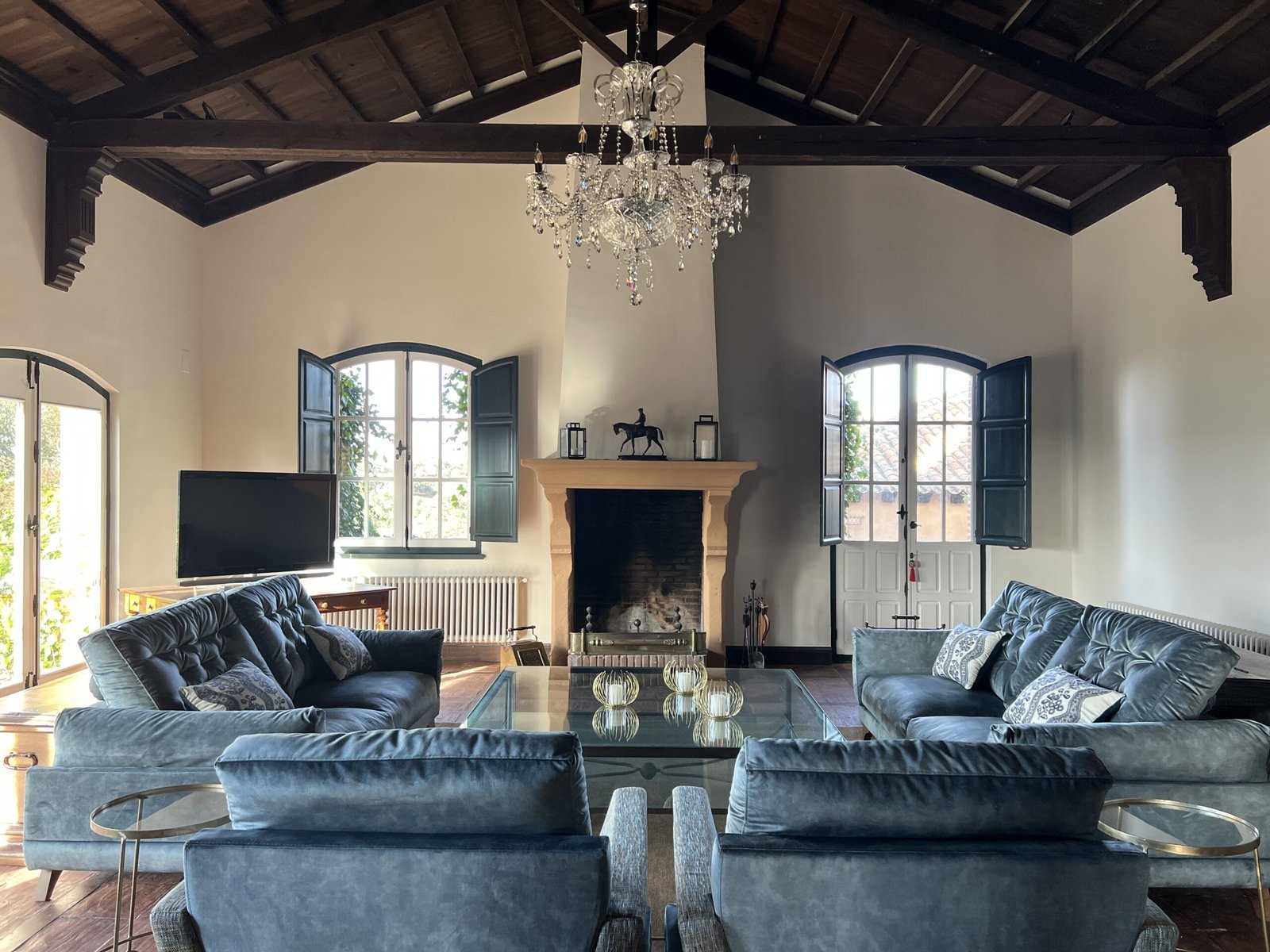 Salón principal de La Quintina, casa rural en San Pelayo de Guareña, con chimenea, sofás y sillones, ventanas con vistas al campo y ambiente acogedor.